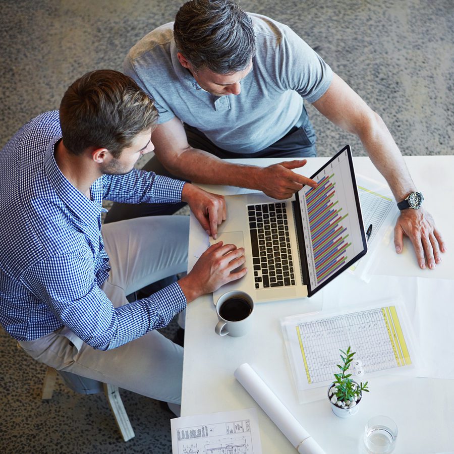 Shot of two colleagues using a laptop in a meeting at the office